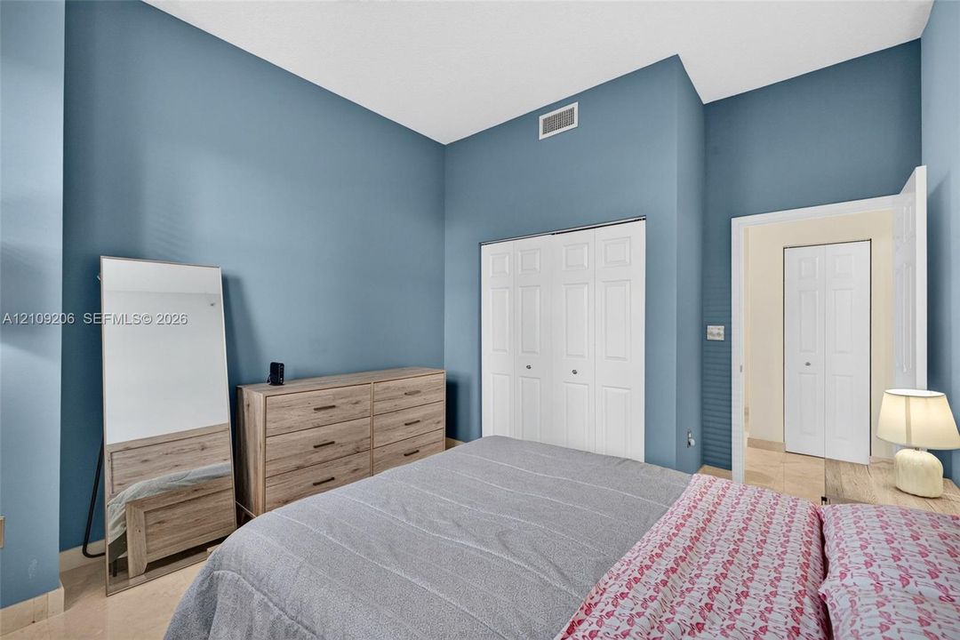 High-ceiling room featuring blue-painted walls, tile flooring, and two white bi-fold closet doors