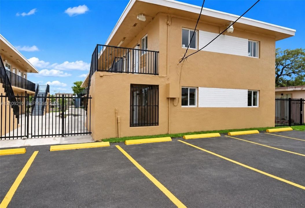 Two-story building featuring stucco exterior, metal railings, exterior staircases, and dedicated asphalt parking area