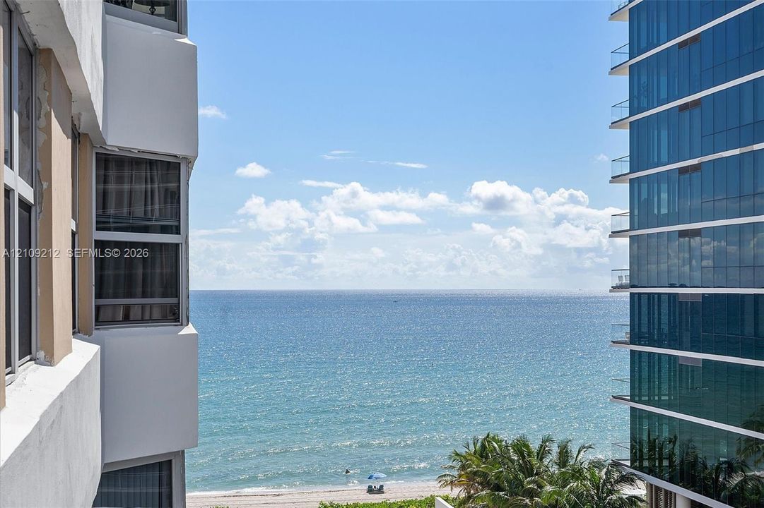 Oceanfront expanse featuring floor-to-ceiling windows, white structural exterior, and glass-paneled building facade
