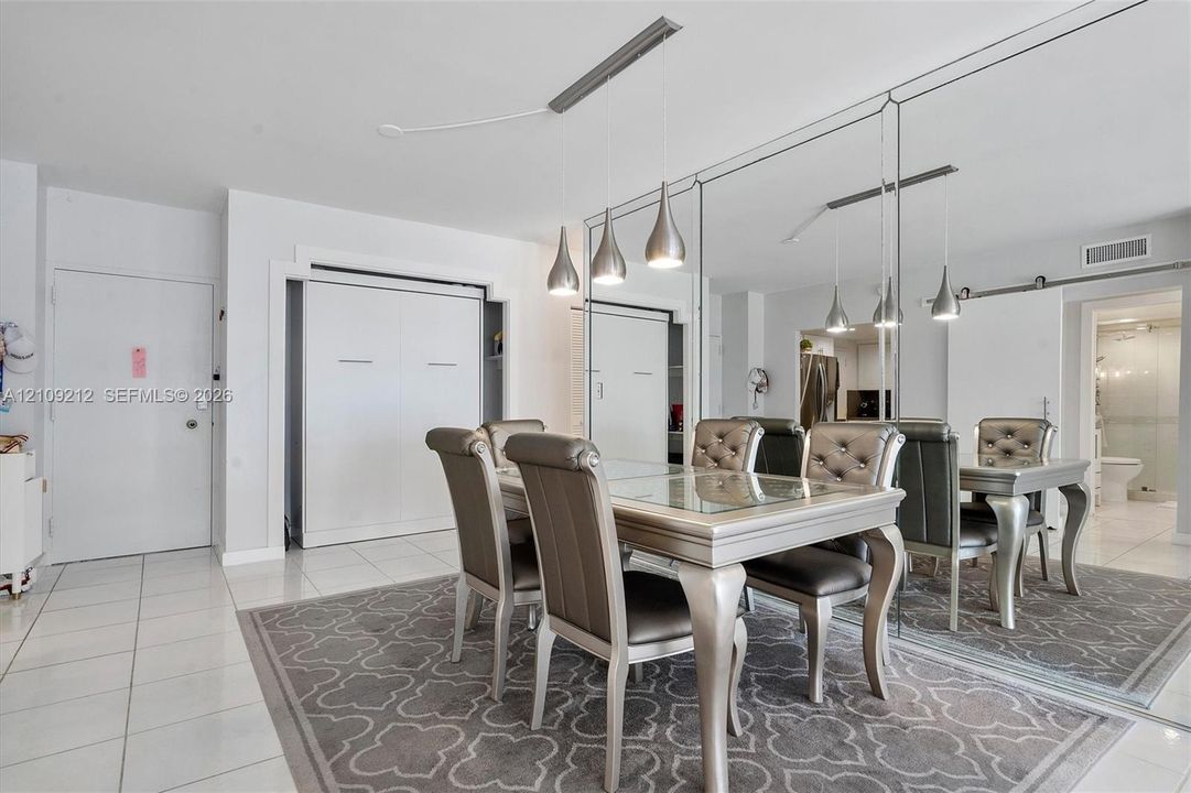 Large mirrored wall paneling, tile flooring, recessed overhead lighting, and built-in wall cabinetry