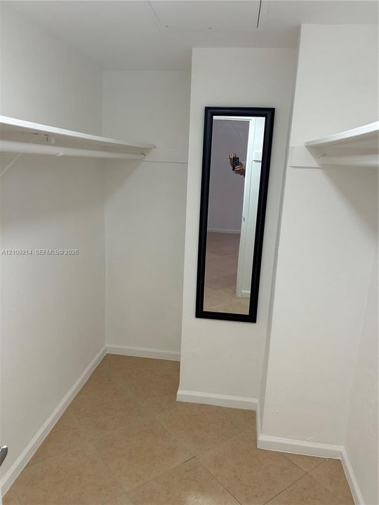 Walk-in storage space featuring ceramic tile flooring, built-in shelving