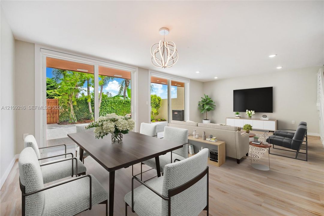 Open-concept space featuring wood-finish flooring, recessed lighting, a modern spherical chandelier, and two sets of large sliding glass doors providing outdoor access