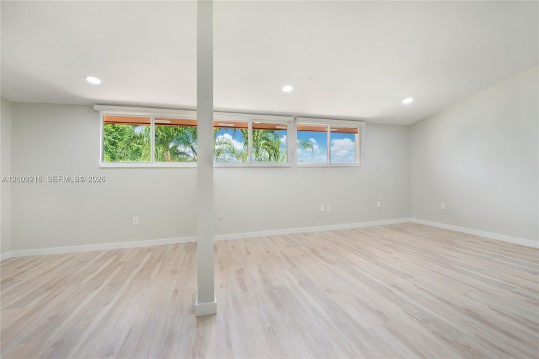 Interior space featuring wood-finish flooring, recessed lighting, and expansive horizontal windows with exterior greenery