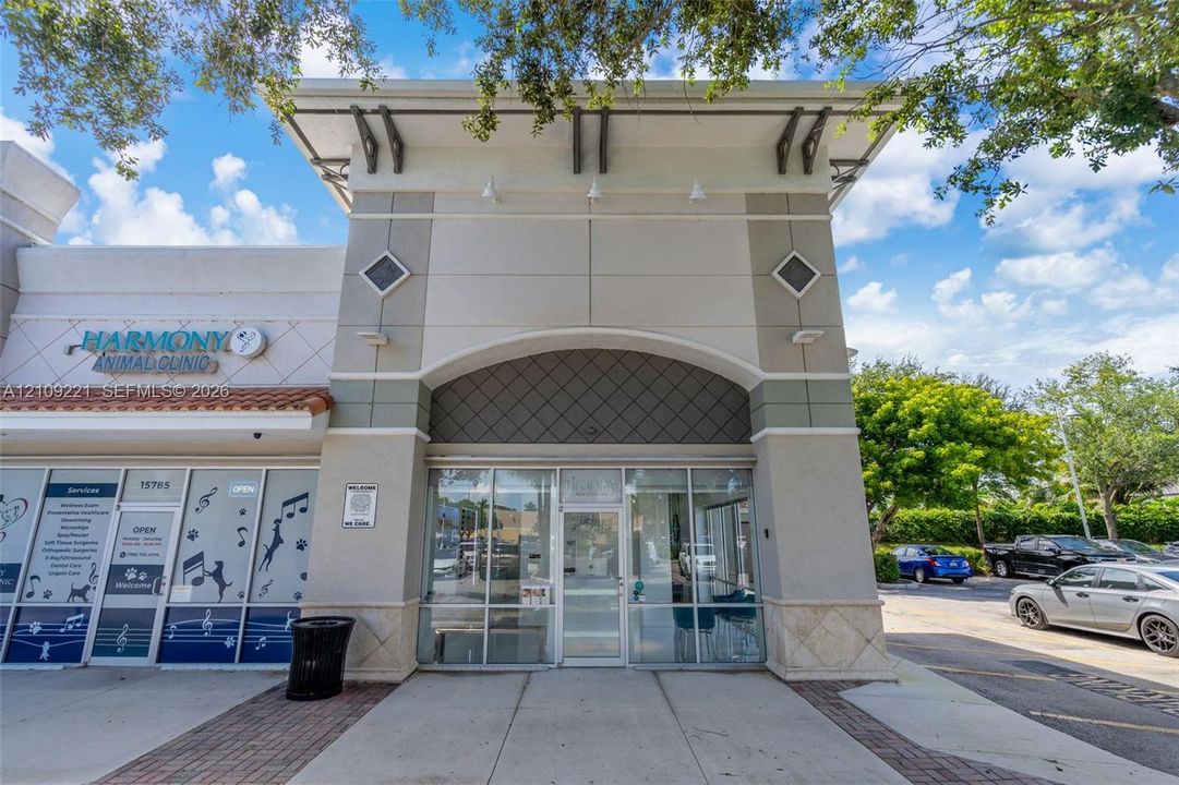 Commercial storefront featuring a high-profile stucco facade, floor-to-ceiling glass display windows, architectural metal corbels, and a decorative diamond-patterned accent wall