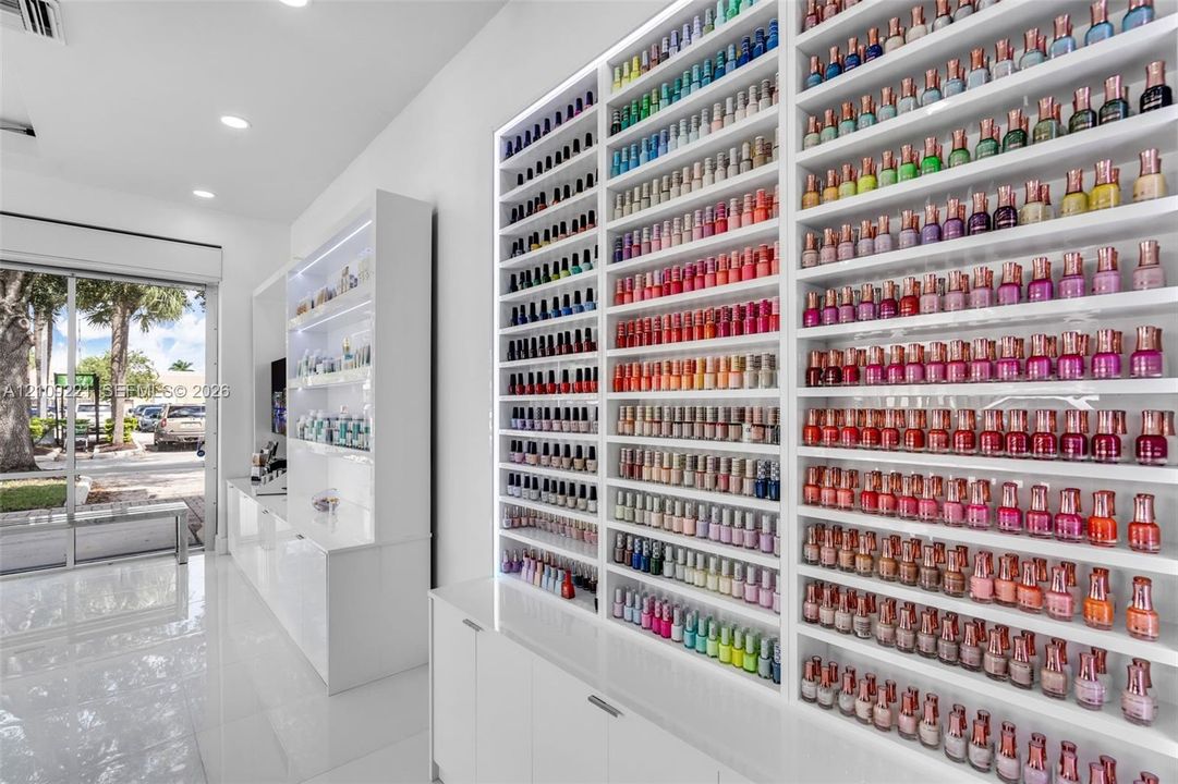 Custom floor-to-ceiling built-in shelving with integrated LED lighting, high-gloss white cabinetry, and polished tile flooring