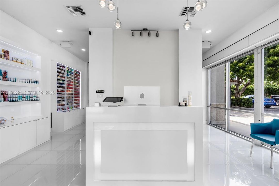 Reception area featuring high-gloss tile flooring, floor-to-ceiling glass wall, built-in display shelving, and pendant lighting