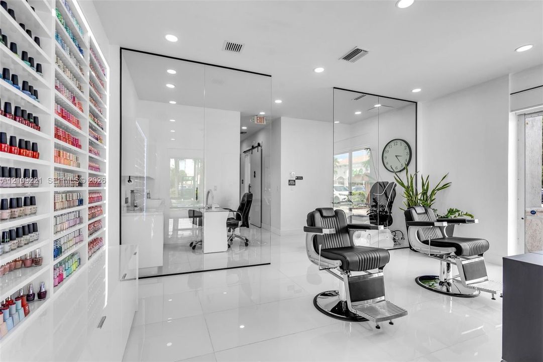 Floor-to-ceiling built-in product shelving with integrated LED lighting, expansive glass wall partitions, and polished tile flooring