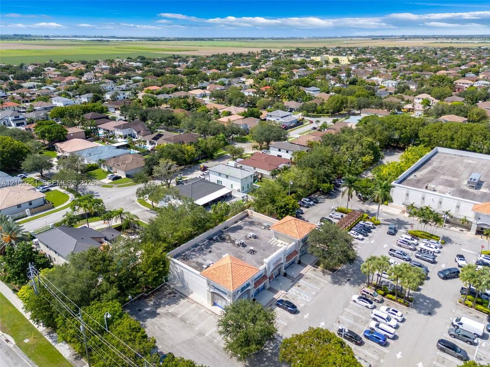 Commercial property featuring a Mediterranean-style roof with terracotta tiles, dedicated asphalt parking lot, and perimeter landscaping