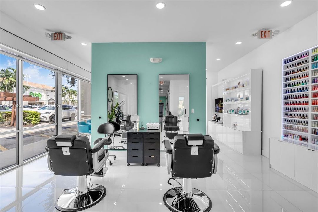 Retail space featuring polished tile flooring, floor-to-ceiling storefront windows, recessed lighting, a built-in illuminated product shelving unit, and dual wall-mounted mirror stations