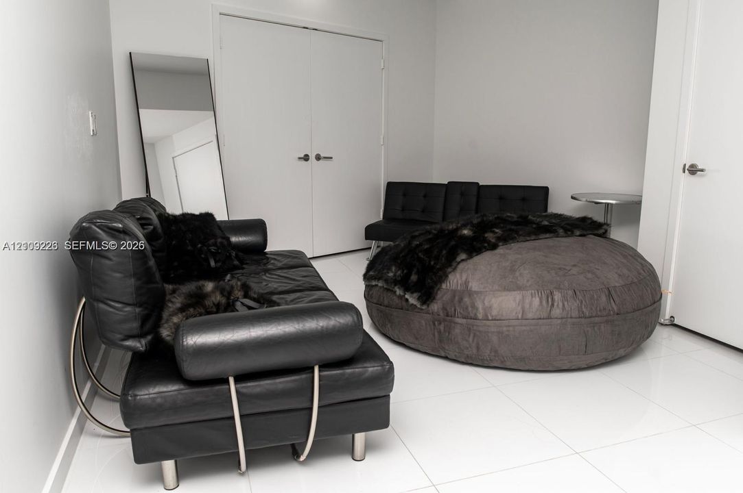 Neutral interior room featuring white tile flooring, double doors with metallic hardware, and a single-panel interior door
