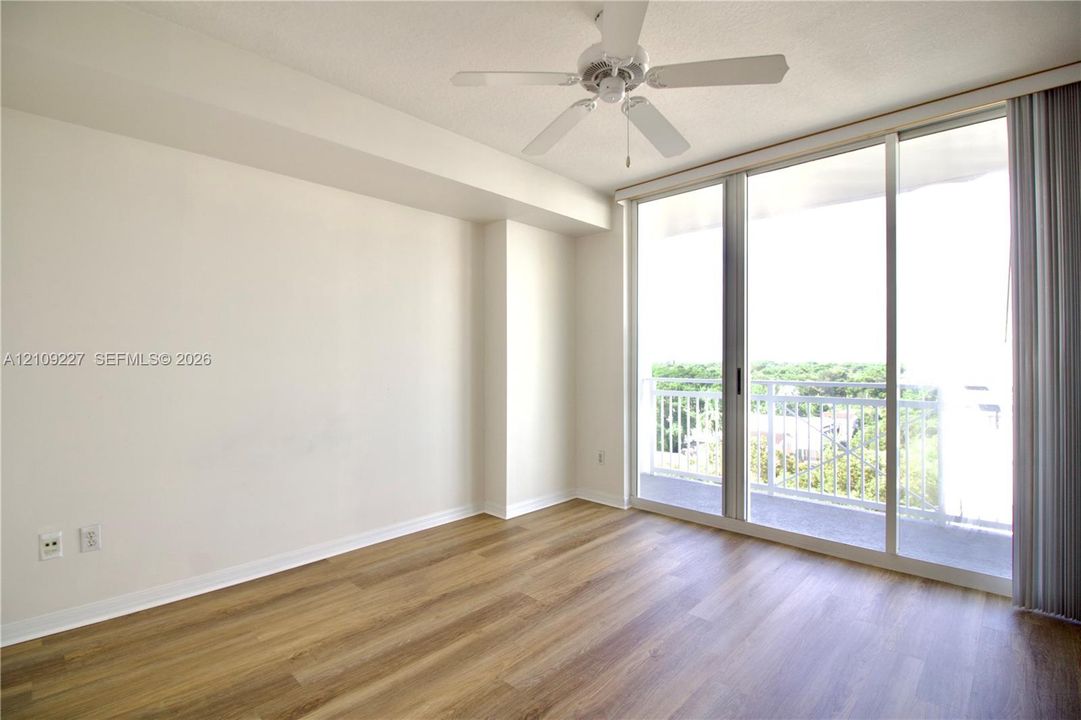 Interior space featuring wood-finish flooring, a ceiling fan, and floor-to-ceiling sliding glass doors opening to a private balcony
