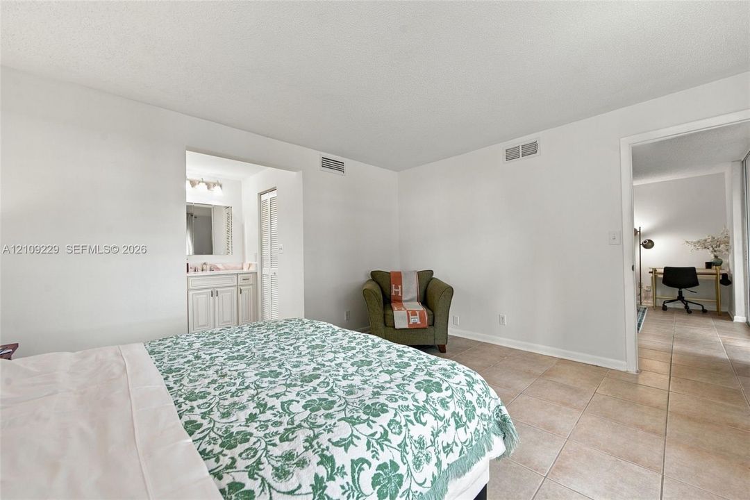 Tile flooring, neutral wall color, and built-in vanity cabinet with mirror and lighting fixture