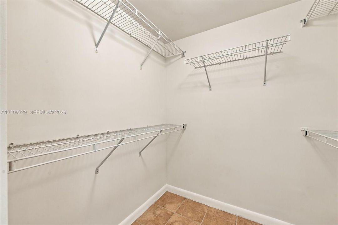 Storage area featuring white walls, tiled flooring, and multiple tiers of installed white wire shelving