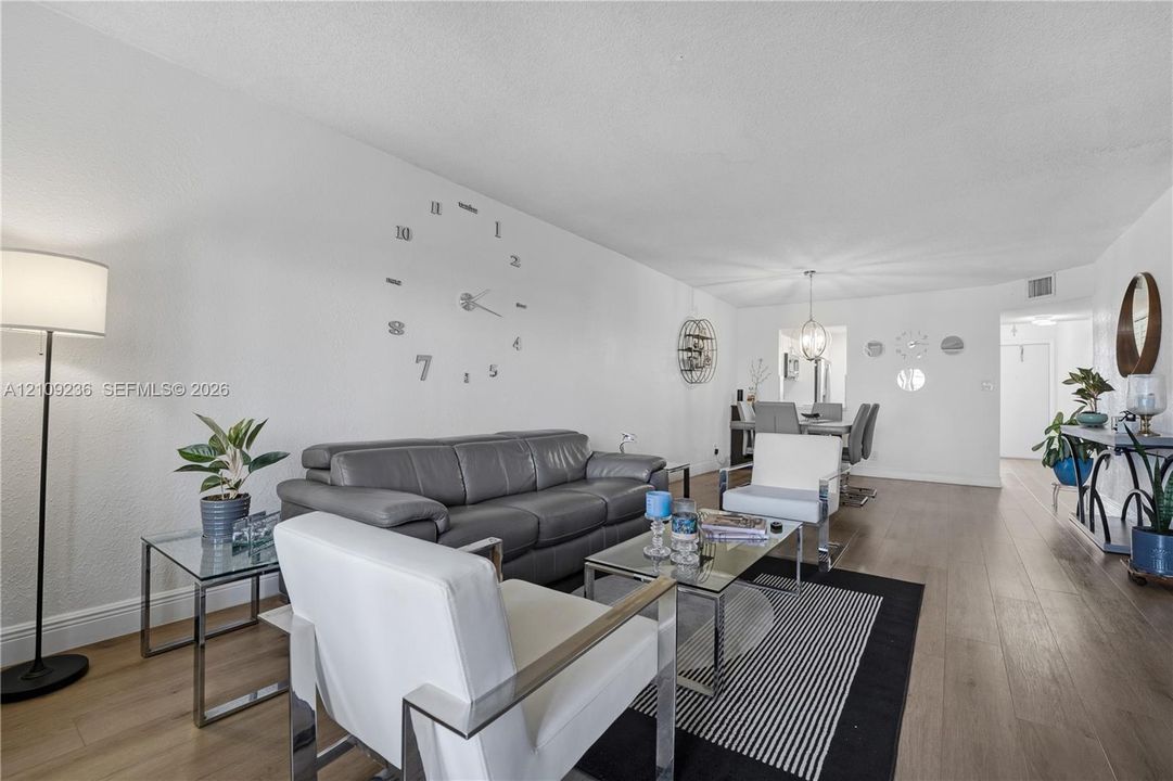 Open-concept interior featuring wood-finish flooring, smooth white walls, and a recessed ceiling lighting fixture