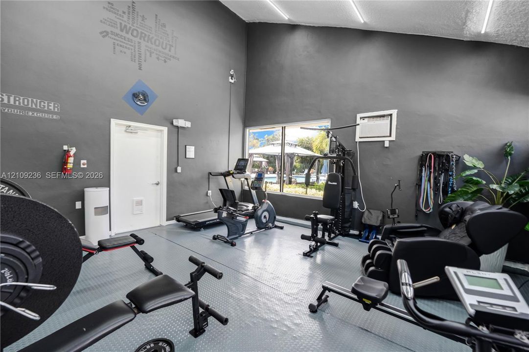 High-ceiling room featuring textured grey walls, durable flooring, and large windows providing natural light
