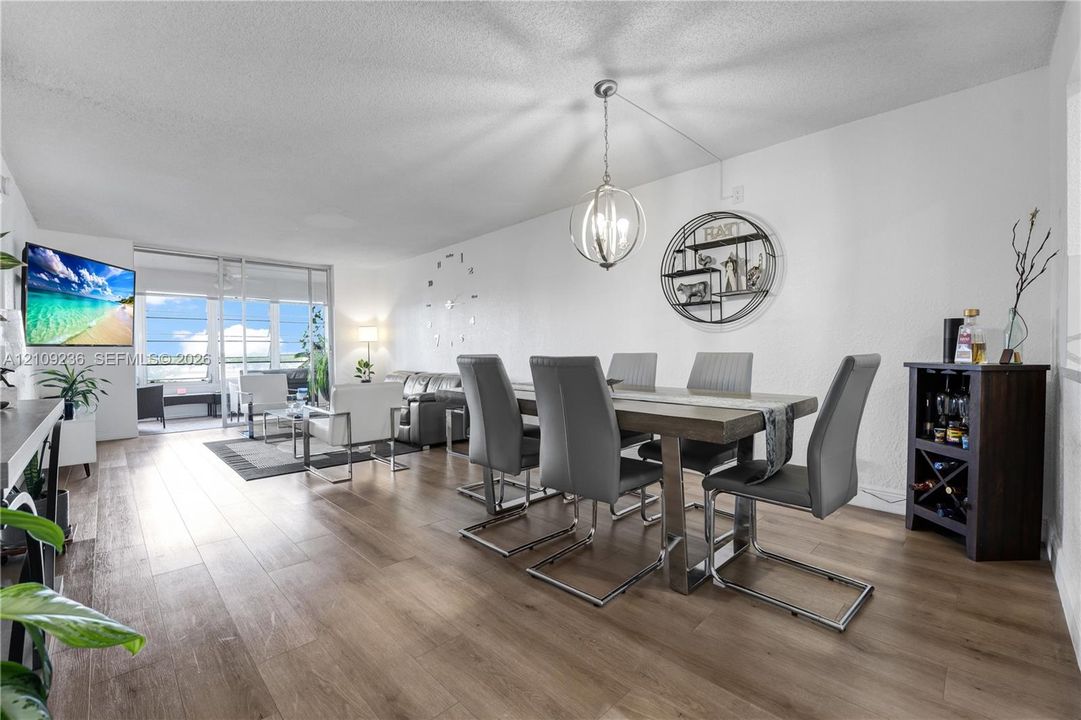 Open-concept interior featuring wood-finish flooring, a modern sphere-style pendant light, and floor-to-ceiling glass sliding doors