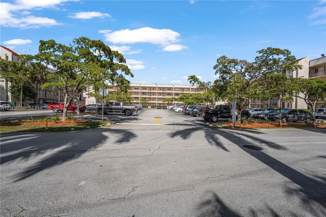 Multi-story residential complex featuring dedicated surface parking and mature landscaping
