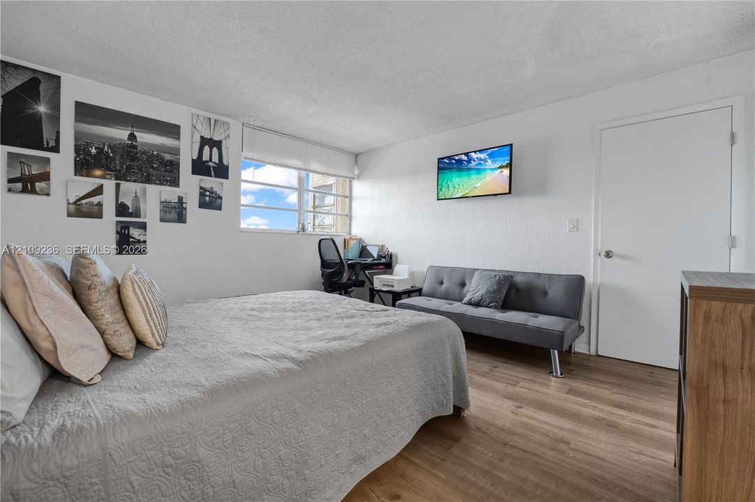 Wood-finish flooring, white walls, and a large multi-pane window with a white roller shade