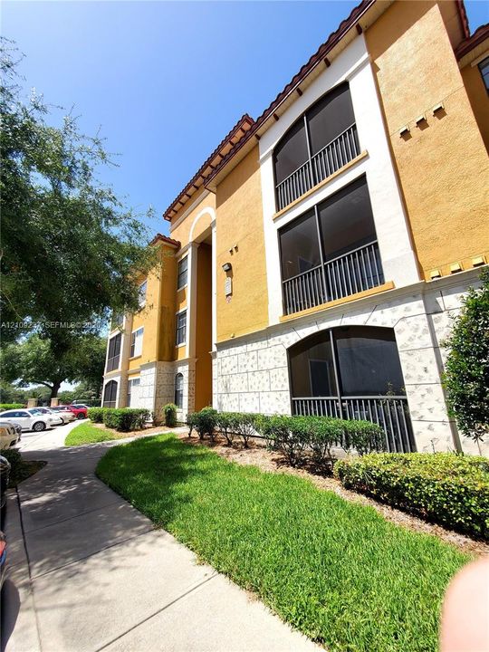 Multi-story exterior featuring stucco siding, stone veneer base, tile roof accents, and screened balconies