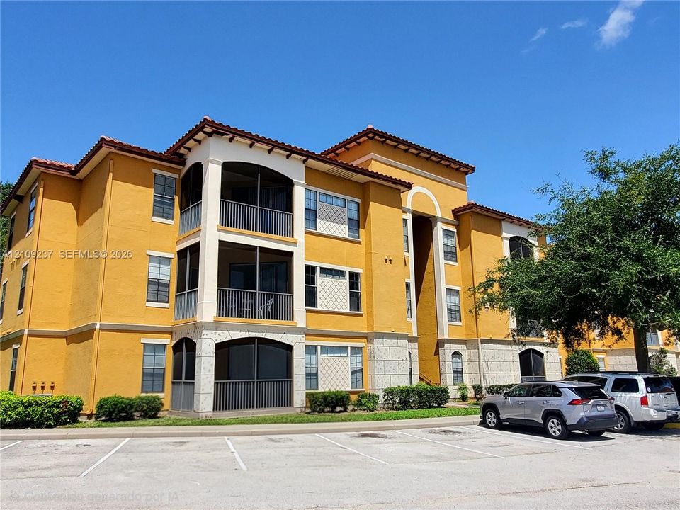 Stucco exterior featuring multi-story screened lanais, decorative tile accents, and a tile roof