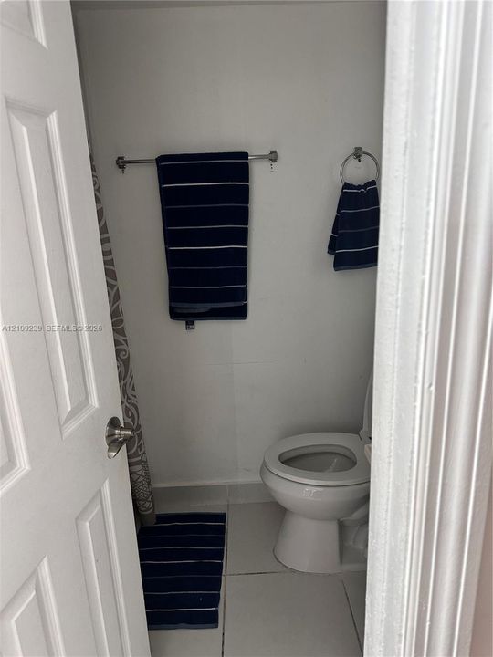 White porcelain toilet with a wall-mounted metal towel bar and ring