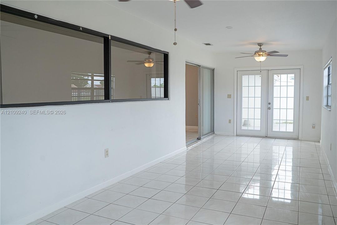 Ceramic tile flooring, white-framed French doors with glass panes, sliding glass door, and dual ceiling fans