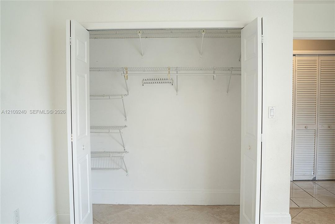 Reach-in closet featuring dual bifold doors, white wire shelving, integrated hanging rods, and an overhead storage shelf