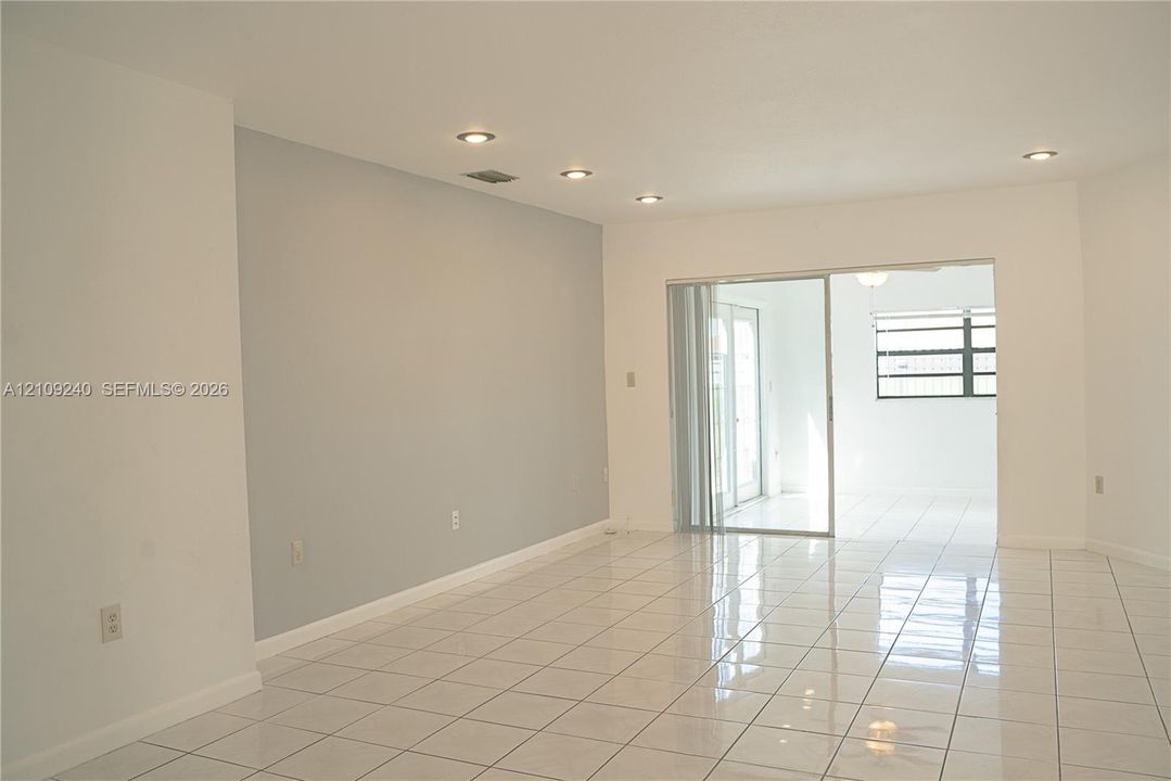 Interior space featuring neutral wall tones, polished tile flooring, recessed ceiling lighting, and a glass sliding door