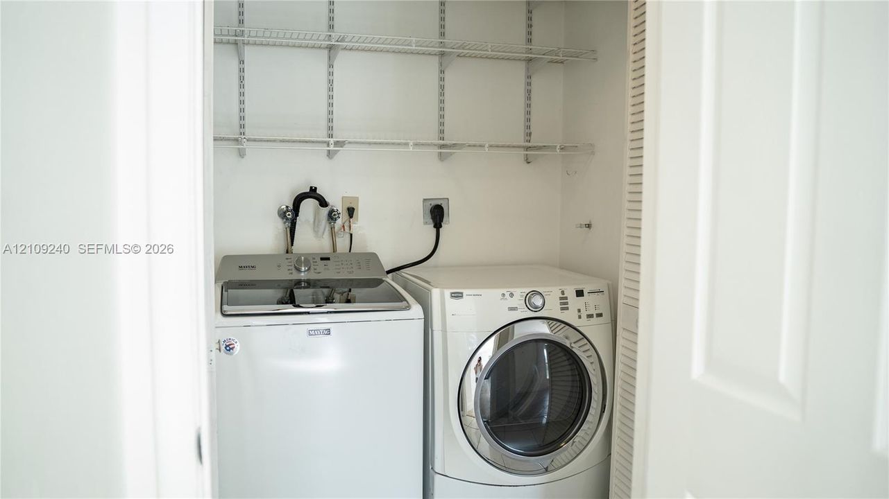 Laundry closet featuring tiered wire shelving and louvered folding doors