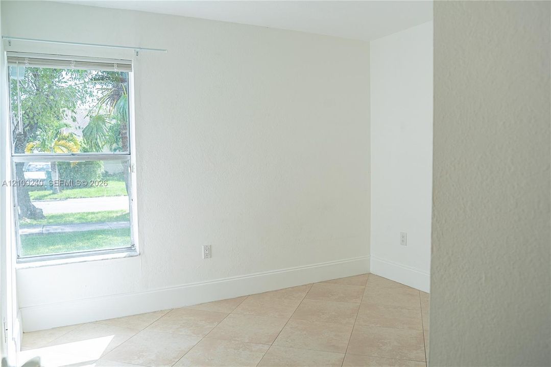 Neutral-toned wall finish, light-colored tile flooring, and single-hung window with a metal frame