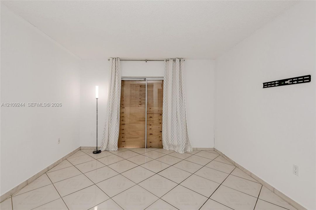 Neutral-toned tile flooring laid in a diamond pattern, sliding bypass closet doors with natural wood panels, and a mounted wall bracket