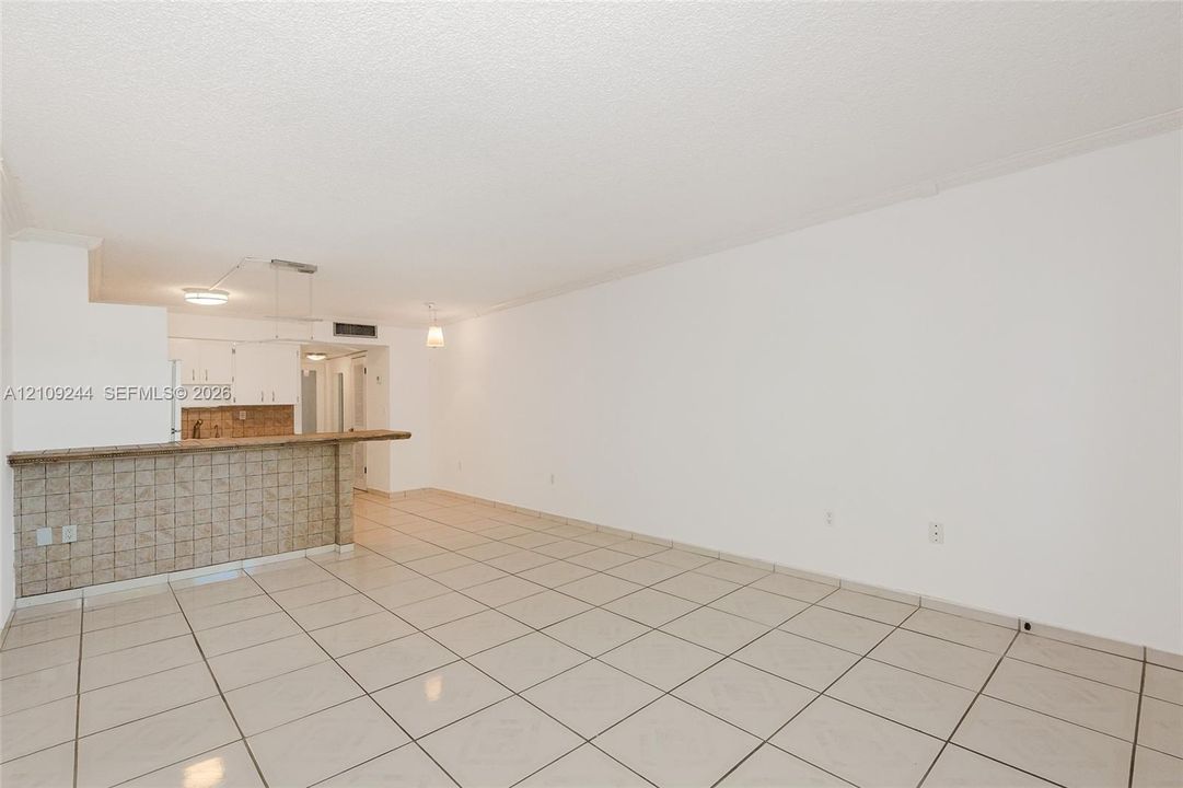 Open-concept area featuring light-toned tile flooring, a peninsula with tiled surfaces, and built-in cabinetry