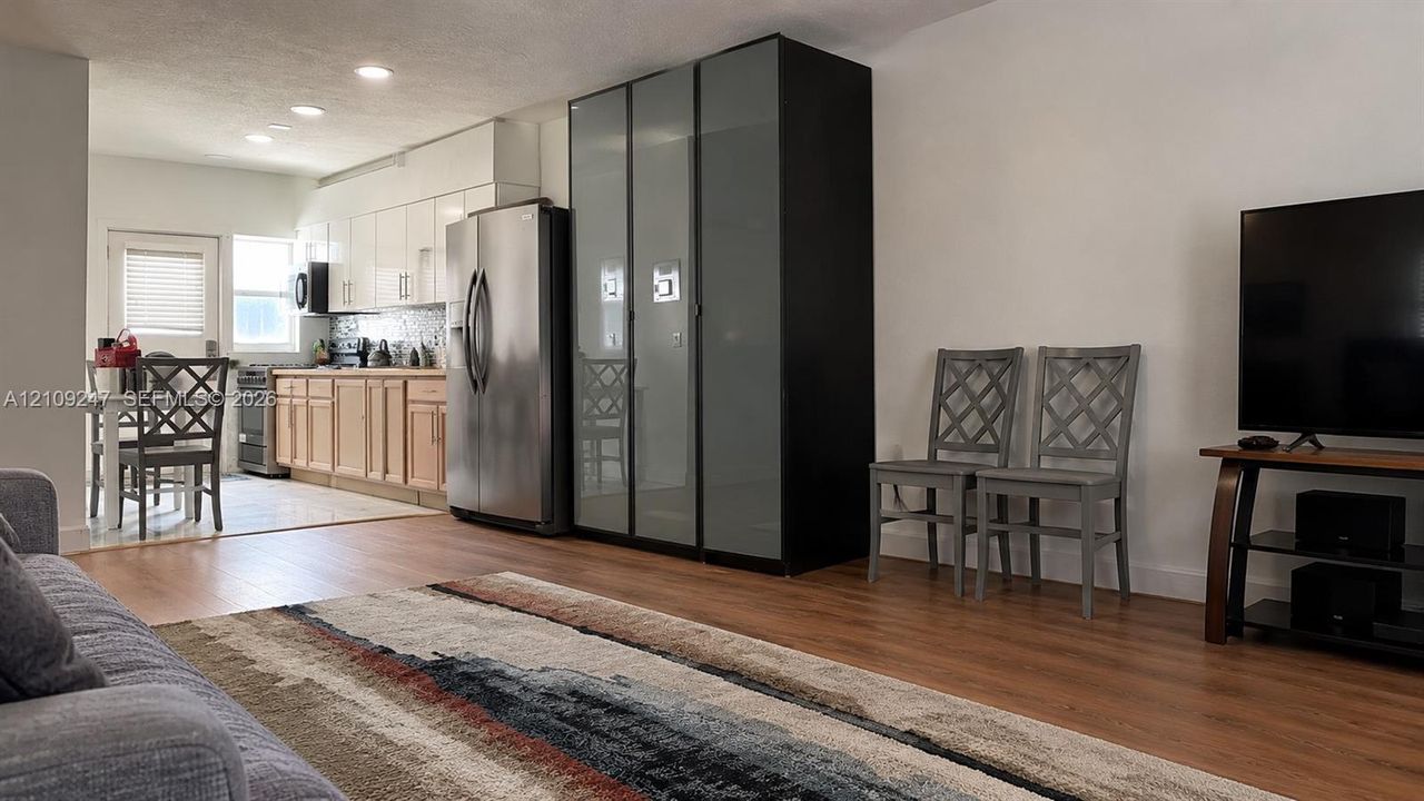 Kitchen featuring wood-finish flooring, two-toned cabinetry, stainless steel refrigerator, and recessed lighting