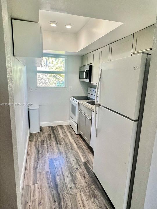 Kitchen featuring wood-finish flooring, recessed lighting, stone-surfaced countertops, and white cabinetry
