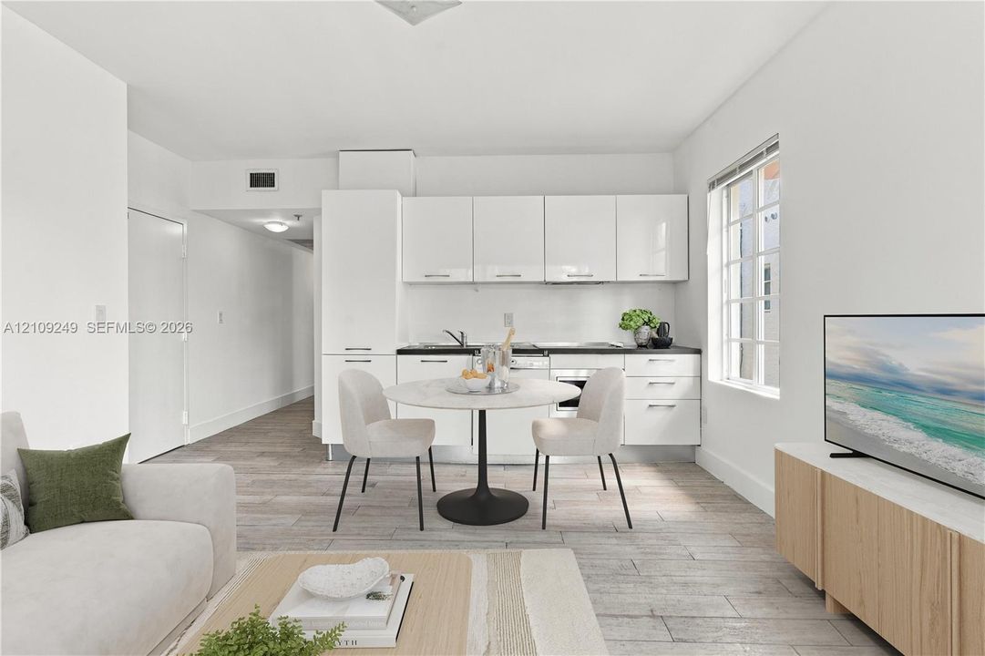 Kitchen featuring white high-gloss cabinetry, dark countertops, wood-finish flooring, and multi-pane window