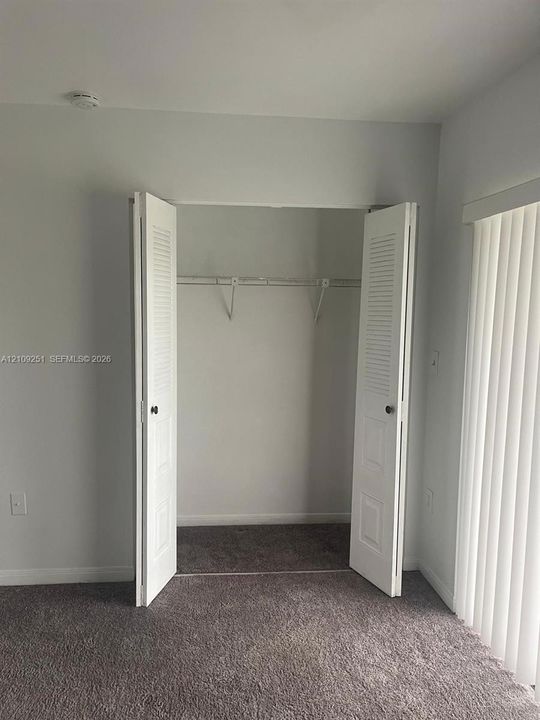 Interior space featuring bi-fold louvered closet doors, wall-to-wall carpeting, and vertical window blinds