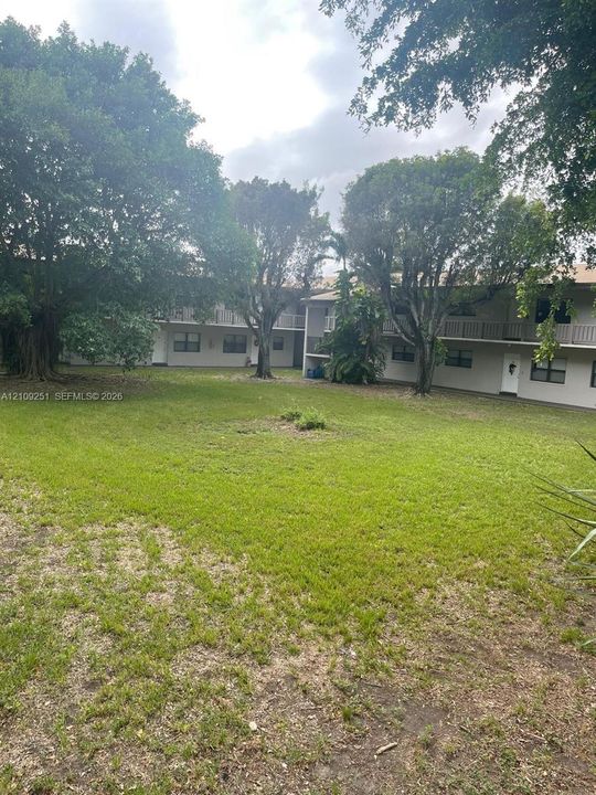 Expansive green space featuring mature trees and multi-story building exterior with balcony railings