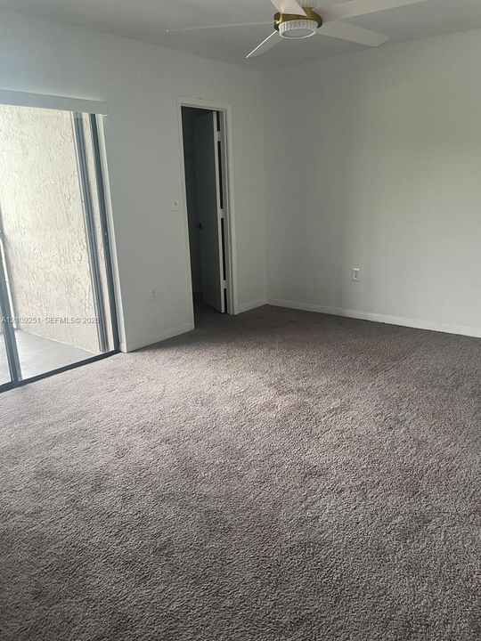 Wall-to-wall carpeting, ceiling fan with integrated lighting, and sliding glass door with access to exterior space