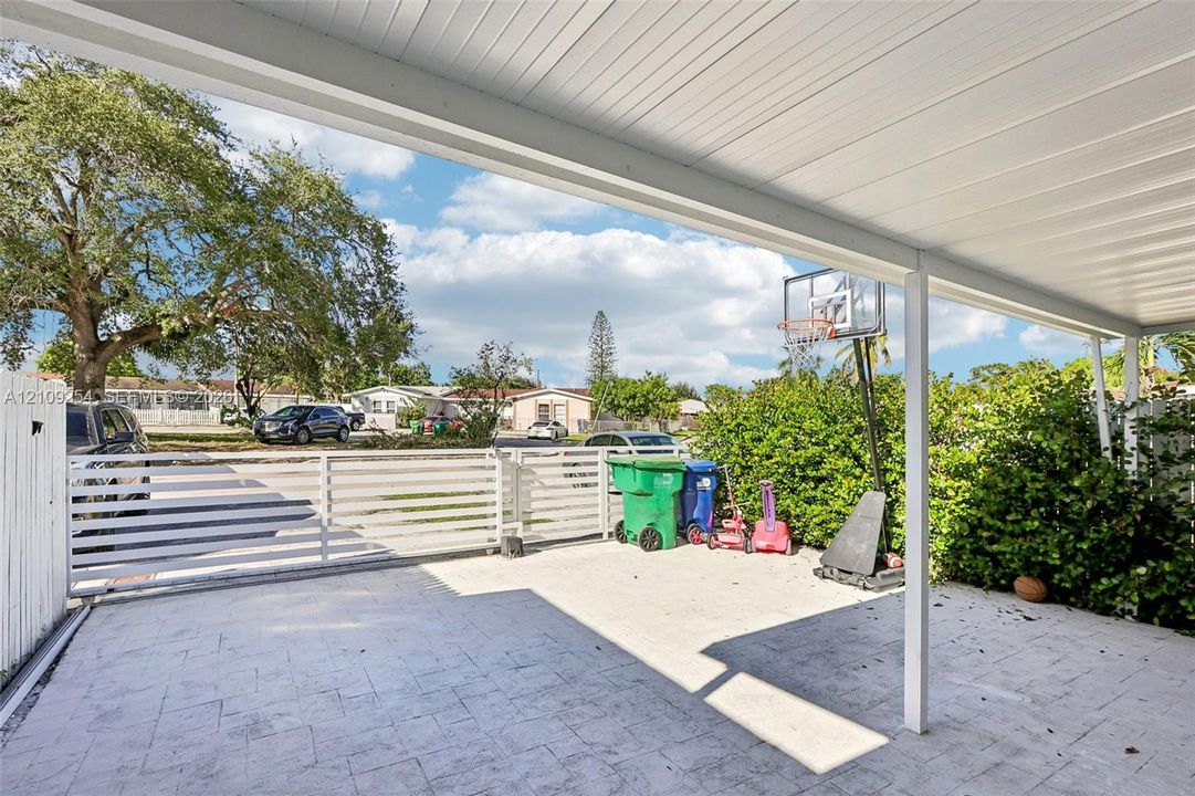 Covered patio featuring a paved surface and white horizontal-slat perimeter fencing