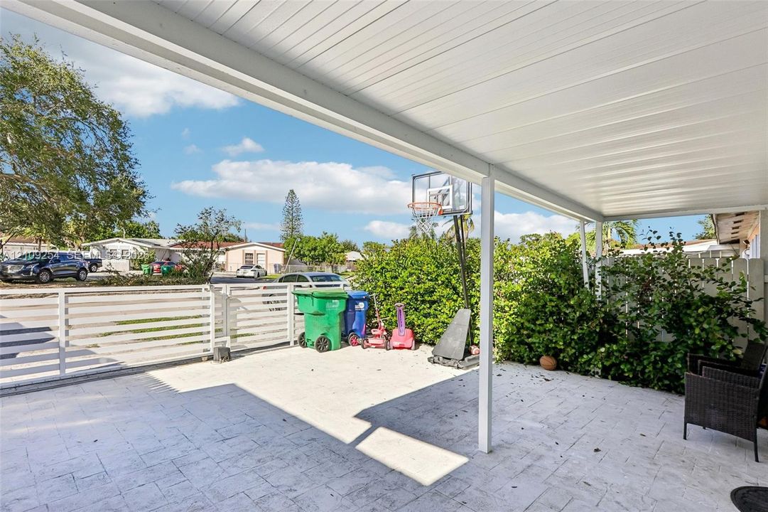 Covered patio featuring a paved floor, a white metal ceiling, and a white horizontal slat fence