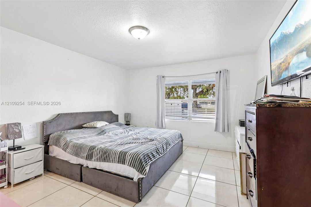 Spacious room featuring large-format tile flooring, smooth-finish walls, and a multi-pane window with natural light