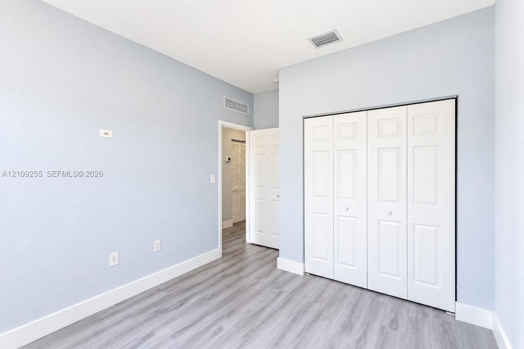 Interior space featuring light-toned walls, wood-finish flooring, and a multi-panel bi-fold closet door