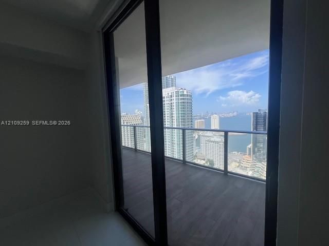 Covered balcony featuring wood-finish flooring, glass panel railings, and full-height sliding glass doors