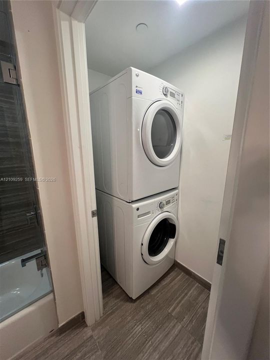 Stacked washer and dryer unit with wood-finish flooring