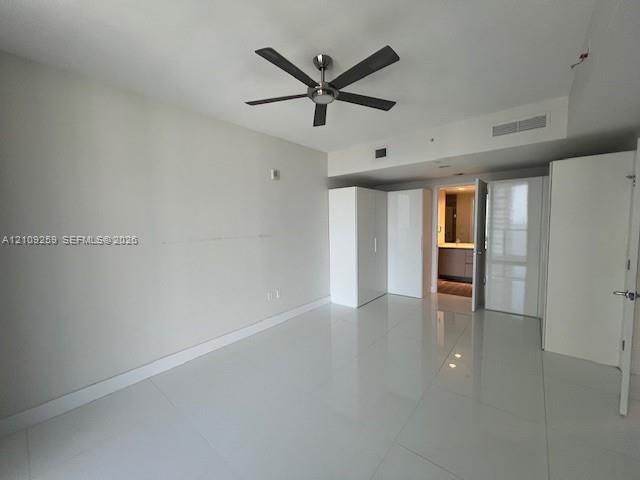 Interior space featuring large-format tile flooring, high-gloss white built-in cabinetry, and a dark-finish ceiling fan