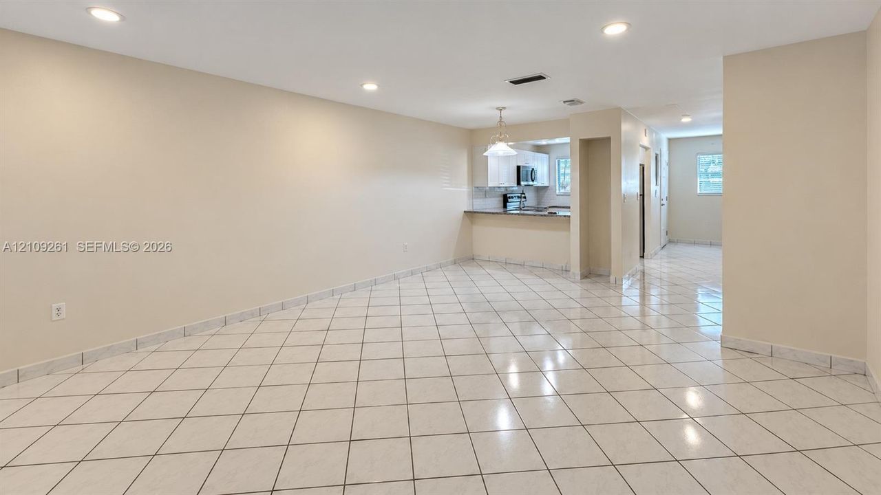 Open-concept interior featuring large-format diagonal tile flooring, recessed lighting, and a breakfast bar with stone-finish countertops