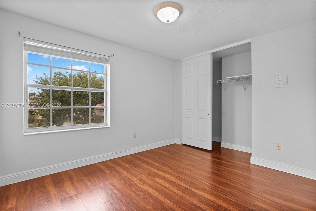 Wood-finish flooring, grid-pane window, flush-mount ceiling lighting, and closet with sliding panel door