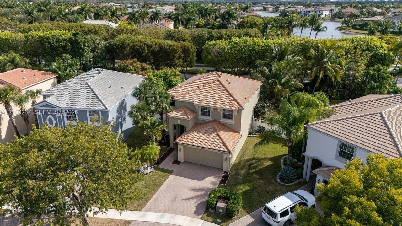 Two-story residence featuring a tile roof, neutral stucco exterior, paver driveway, and an attached two-car garage