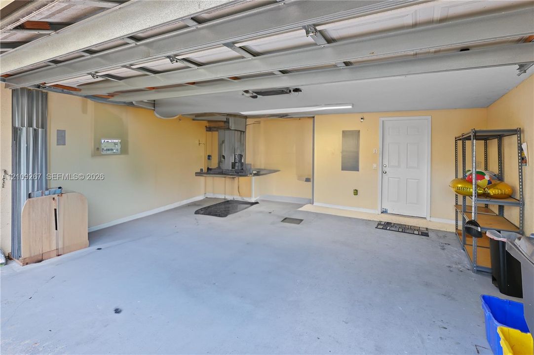Multi-car garage featuring a painted concrete floor, overhead lighting, and an exterior access door