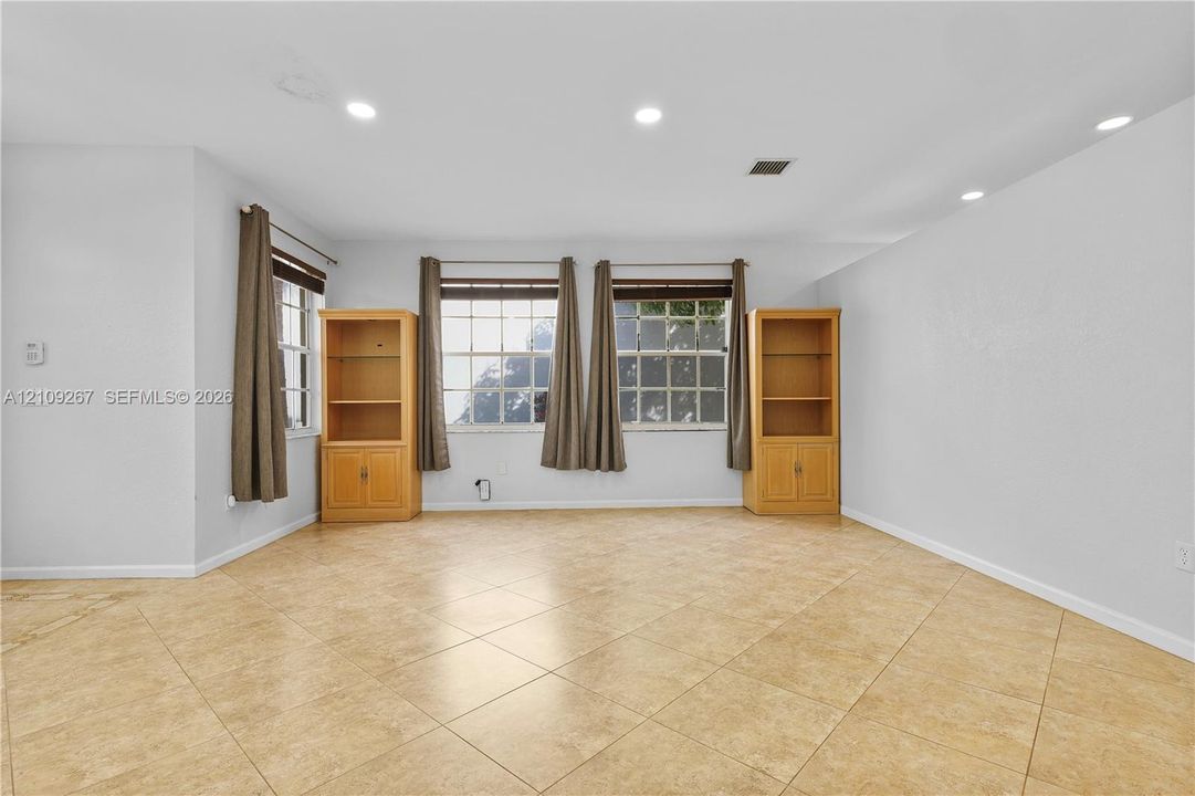 Interior space featuring neutral wall paint, tile flooring, built-in wooden cabinetry, and recessed lighting